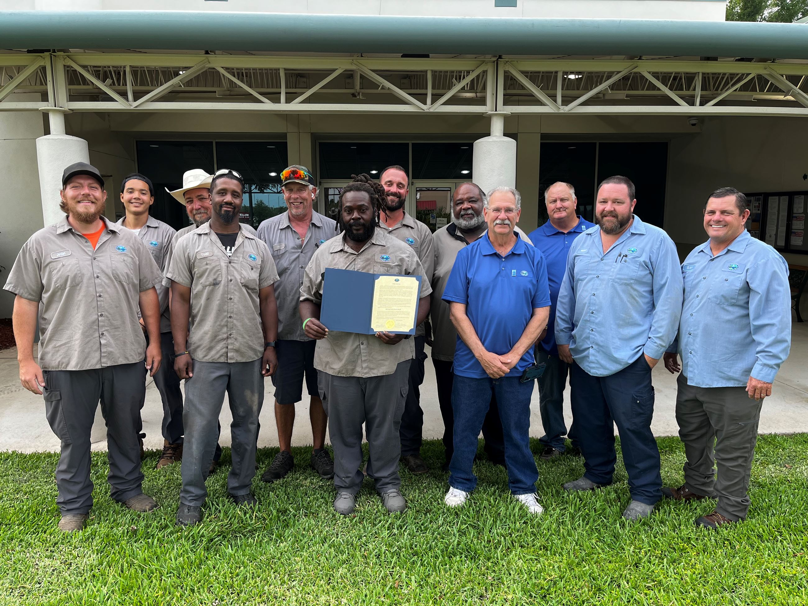 Staff members in blue shirts pose in front of Town Hall