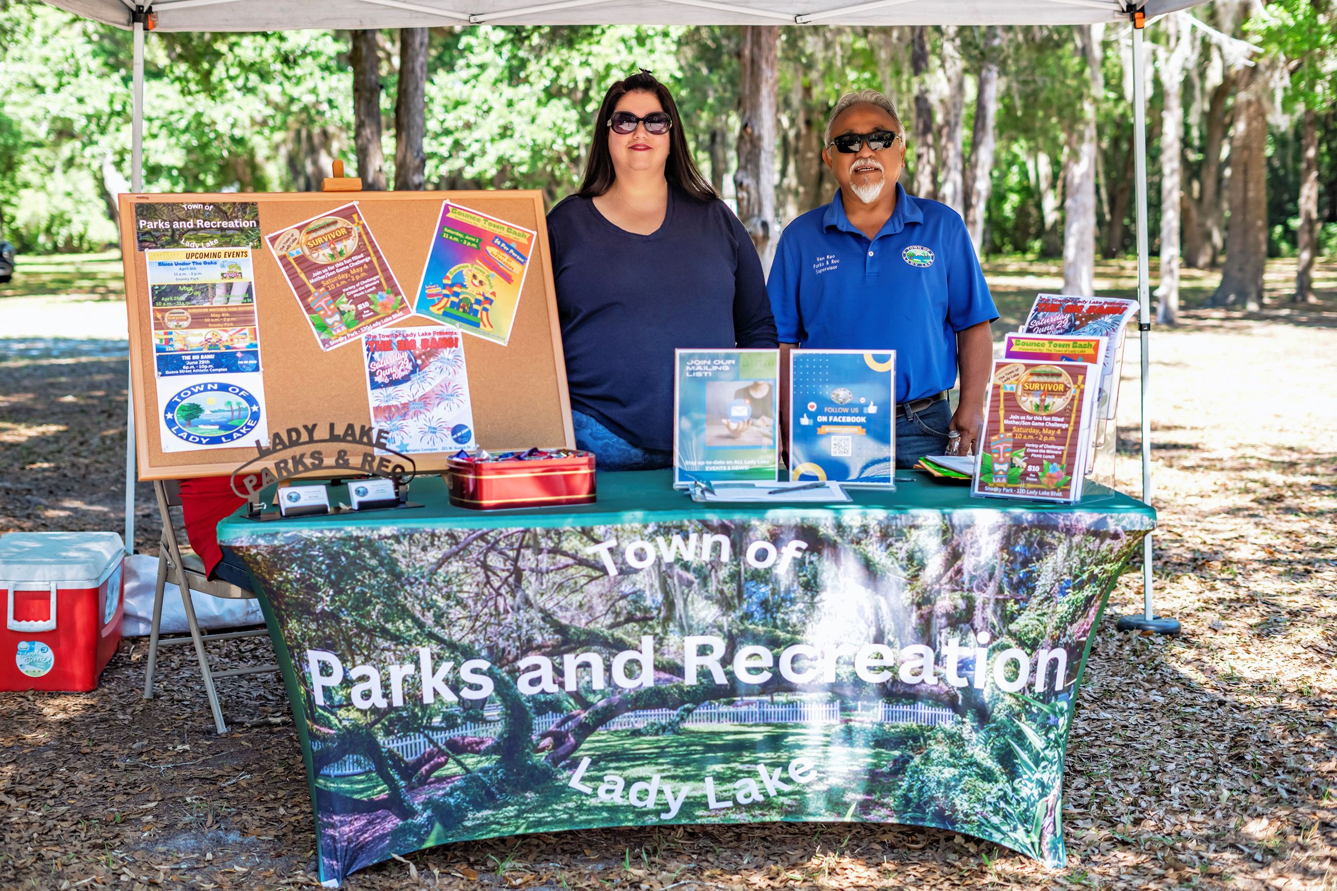 Woman and man stand at Parks & Recreation table at a park