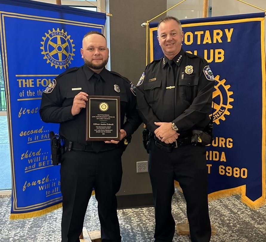 Two male officers standing together, one holding an award
