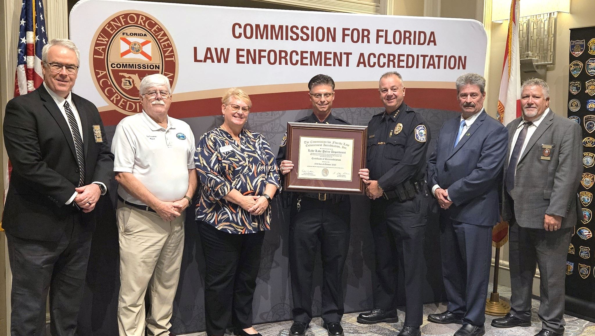Police officers and elected officials pose for a photo holding the accreditation award